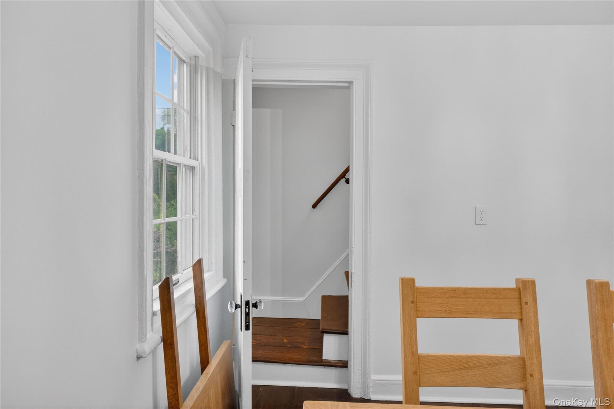 121 Old Glenham Road Fishkill, NY 12524 - Photo 17 of 50 Bright interior with a double-hung window, white trim, and a doorway revealing a side staircase with wood-finish treads and a dark wood handrail.