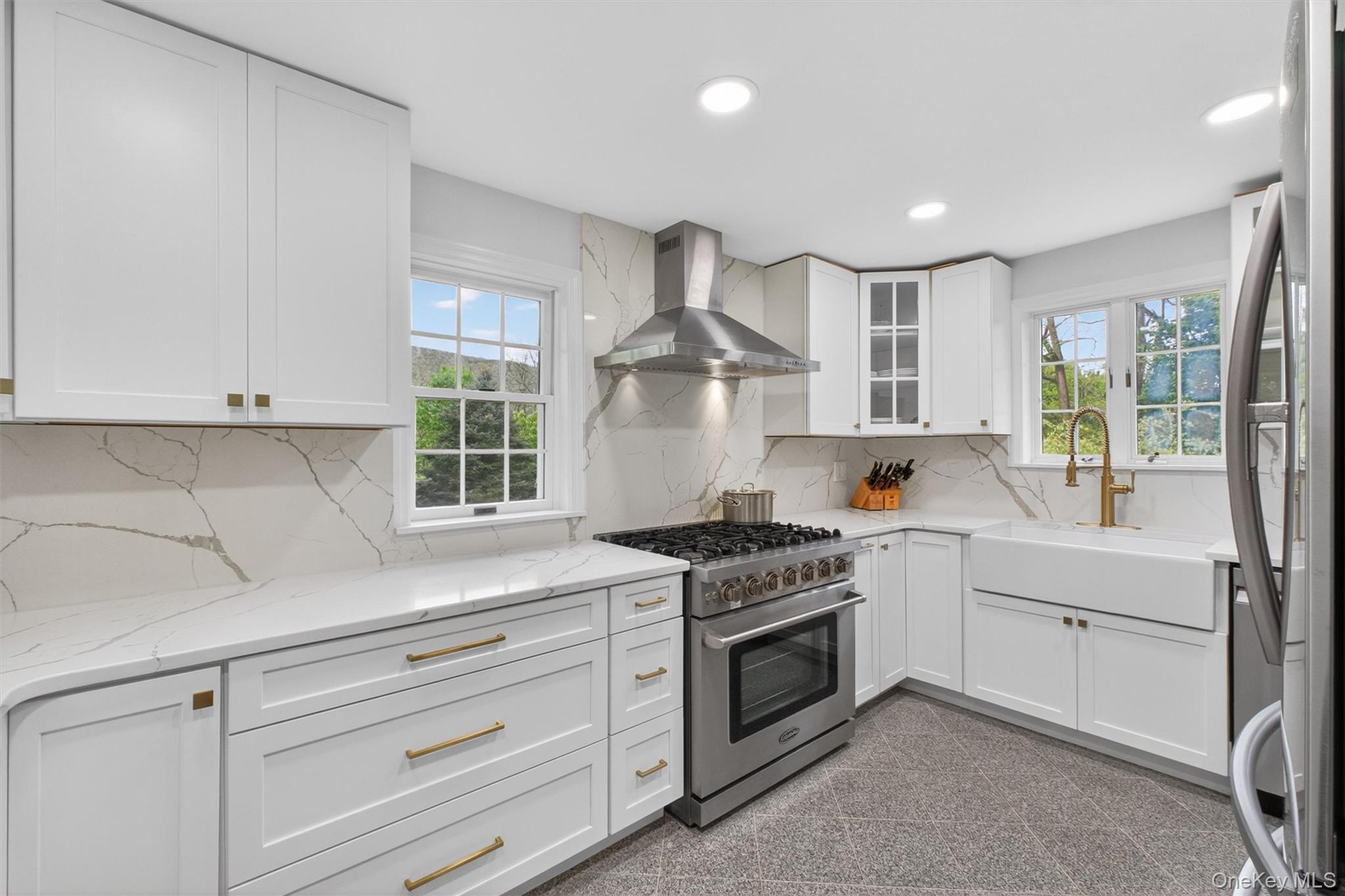 121 Old Glenham Road Fishkill, NY 12524 - Photo 18 of 50 Bright kitchen featuring white cabinetry, white quartz countertops with veining, a stainless-steel range with hood, a white farmhouse sink, recessed lighting and gold ornamentation hardware