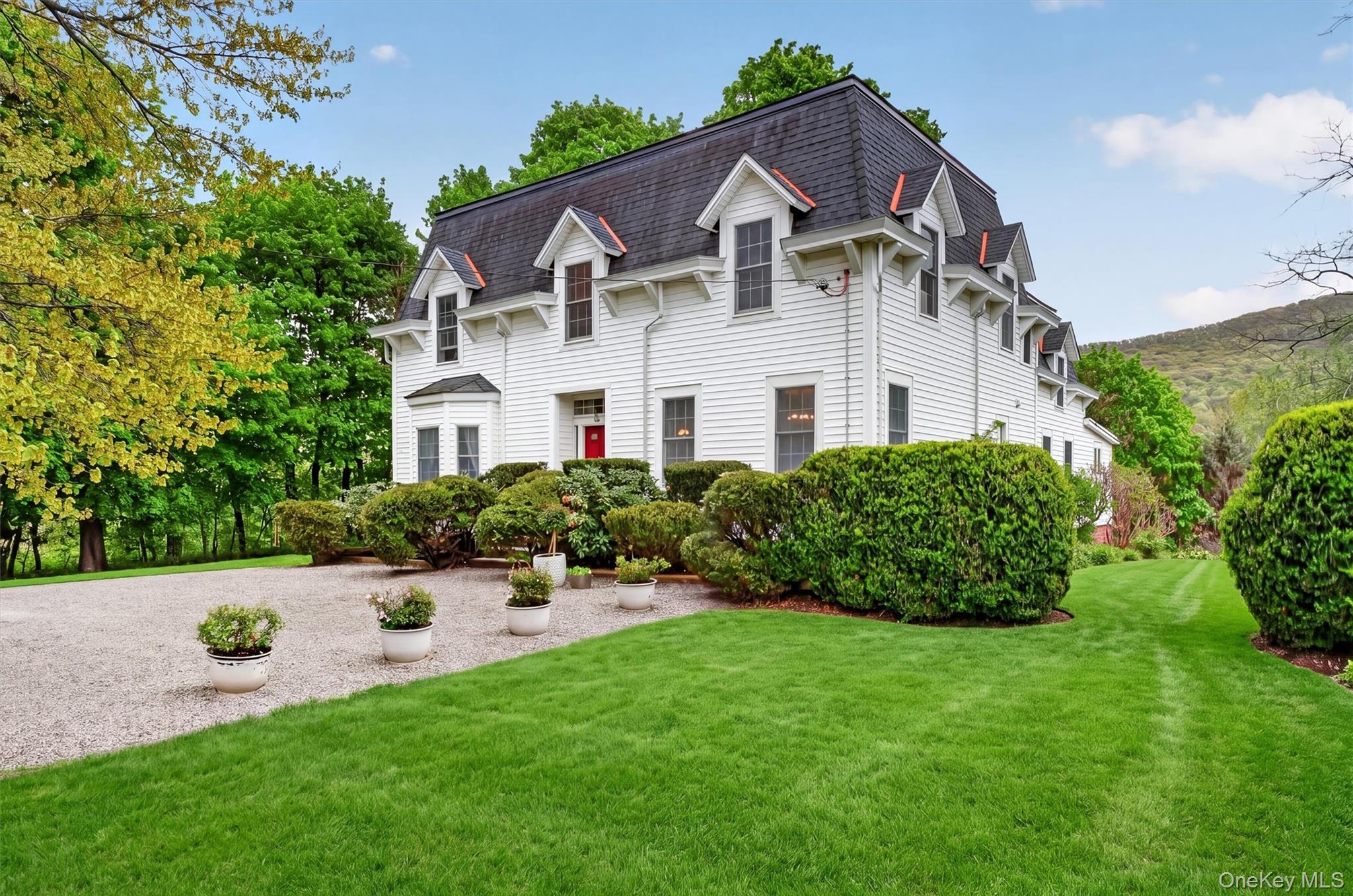 121 Old Glenham Road Fishkill, NY 12524 - Photo 2 of 50 Exterior of colonial residence with red door and mansard roof. Gravel driveway with manicured gardens and lawn surrounding.