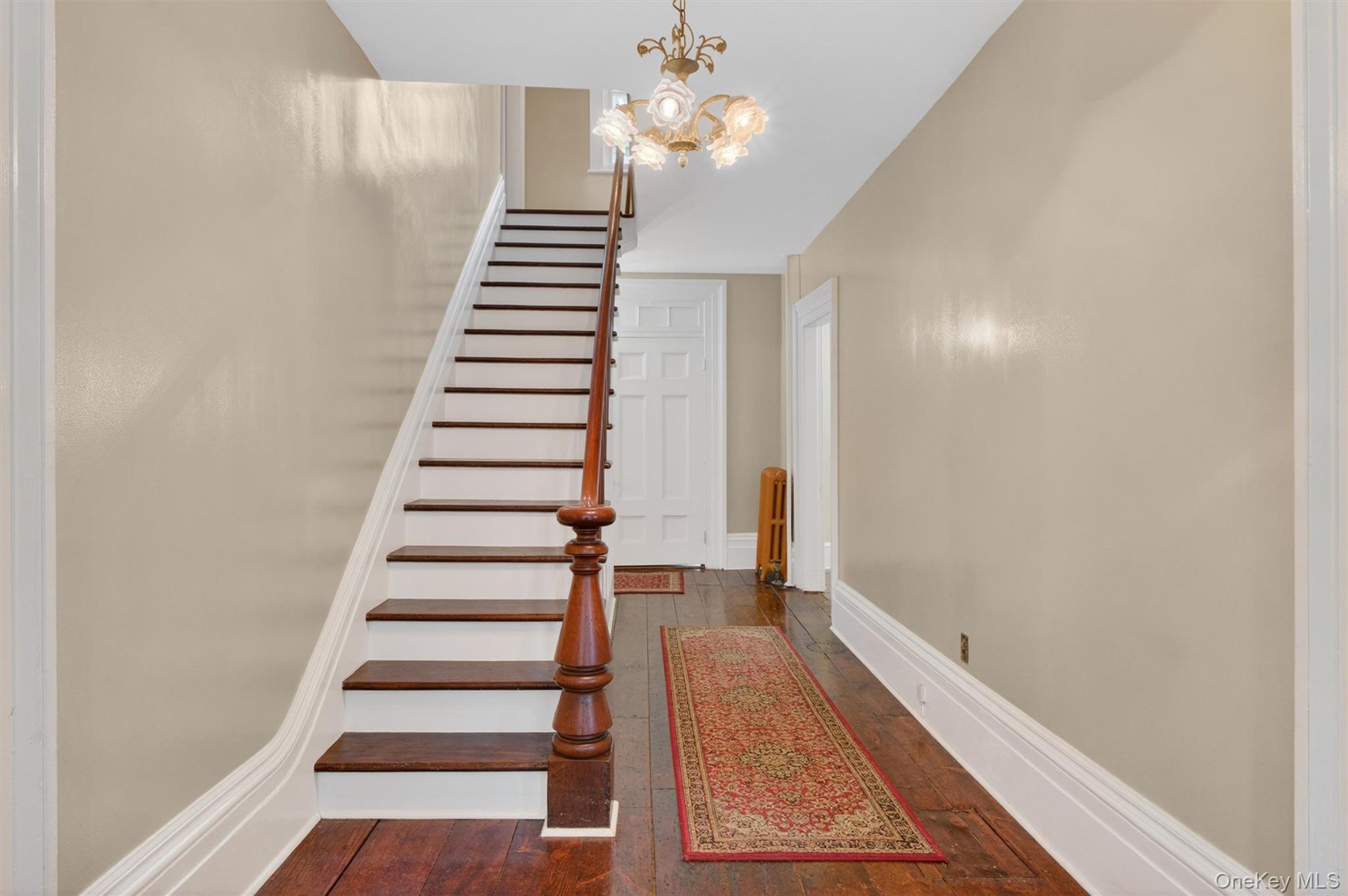 121 Old Glenham Road Fishkill, NY 12524 - Photo 21 of 50 Foyer showcasing hardwood flooring, a classic chandelier, a dark wood staircase with balusters, and hallway leading into other areas.