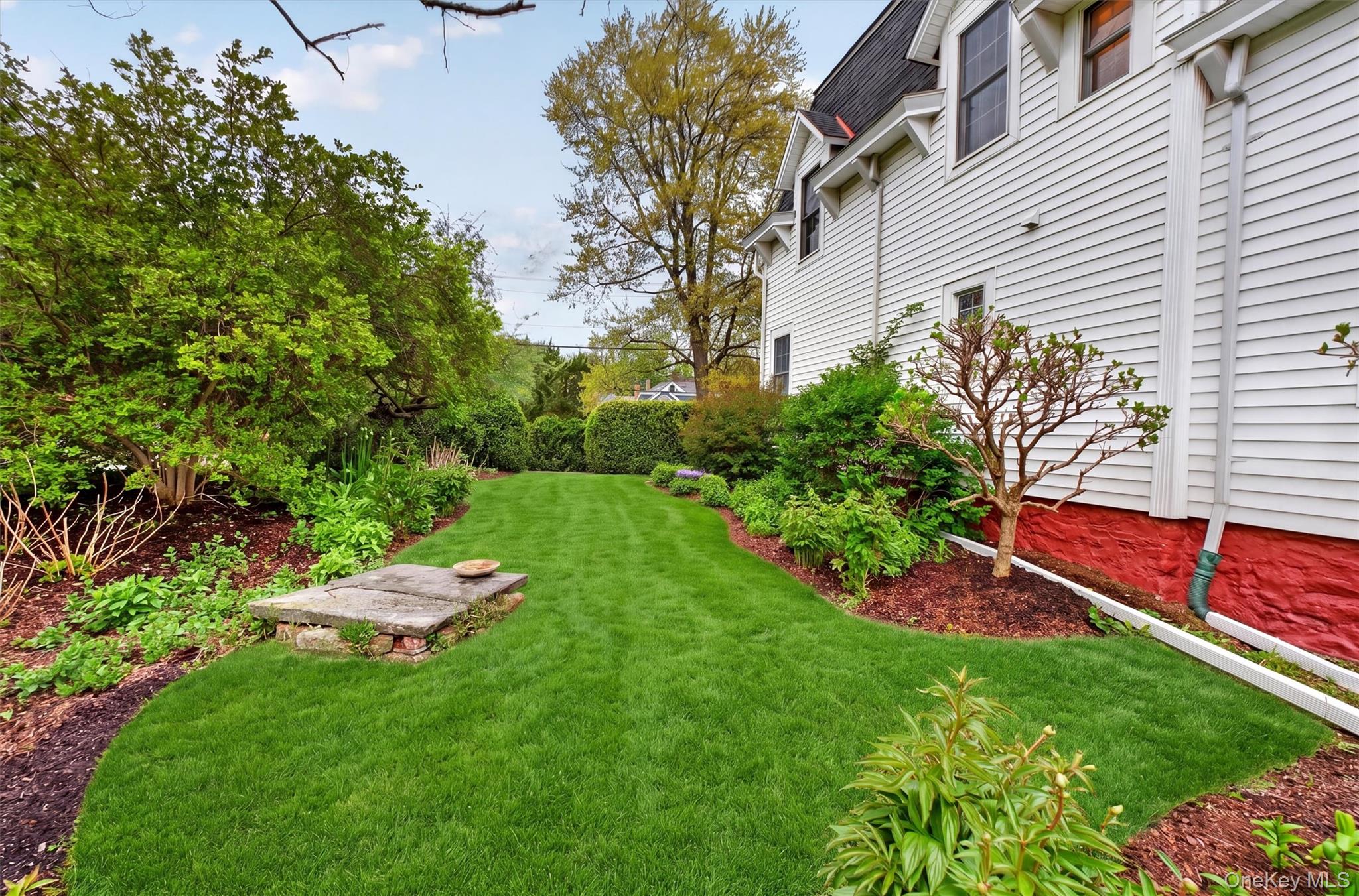 121 Old Glenham Road Fishkill, NY 12524 - Photo 45 of 50 Expansive green lawn framed by manicured hedges, mature trees, and plants, leading to the backyard with views of the hills and mountain.