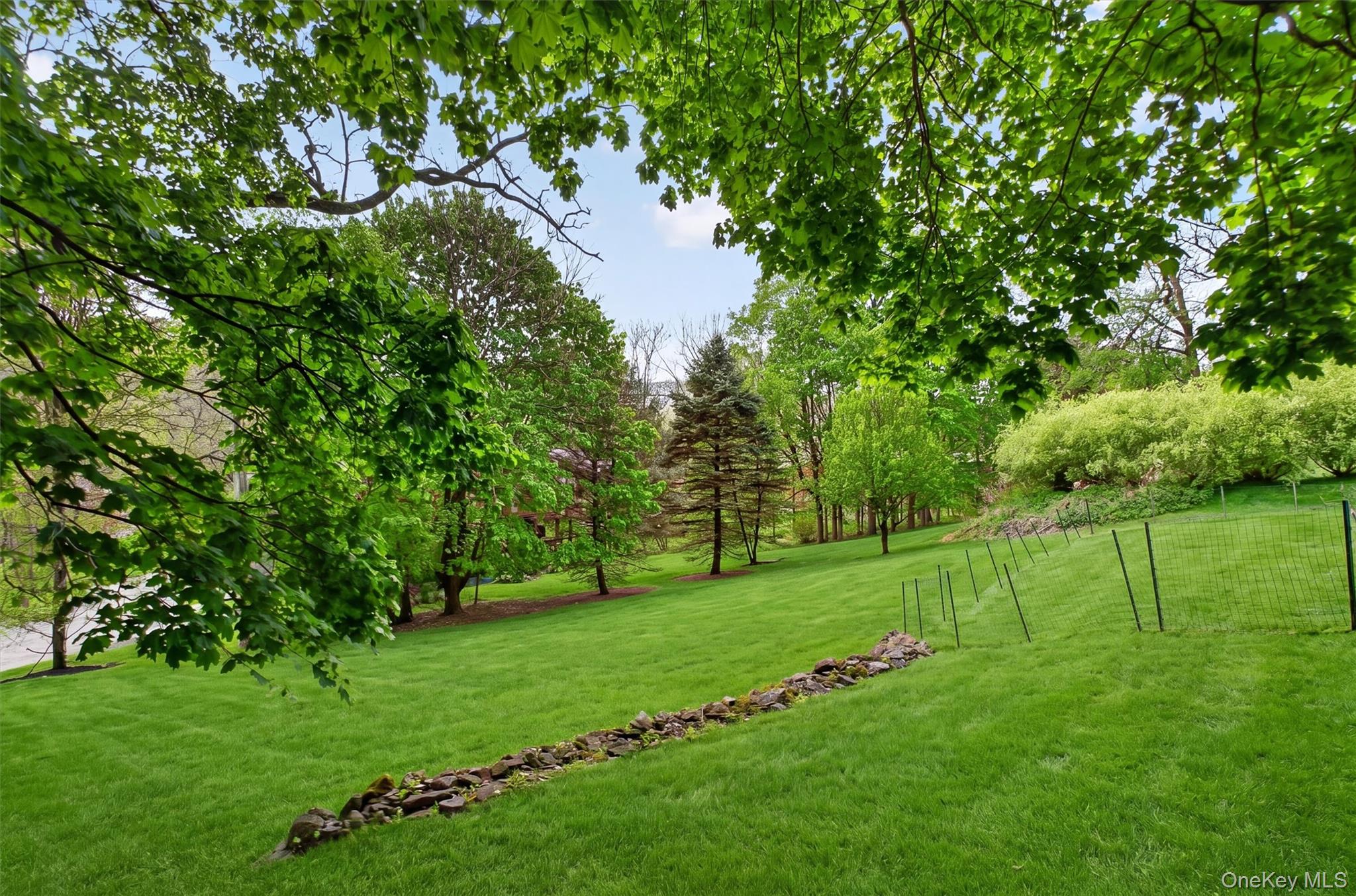 121 Old Glenham Road Fishkill, NY 12524 - Photo 46 of 50 Expansive green lawn with mature trees and a stone-lined wall.