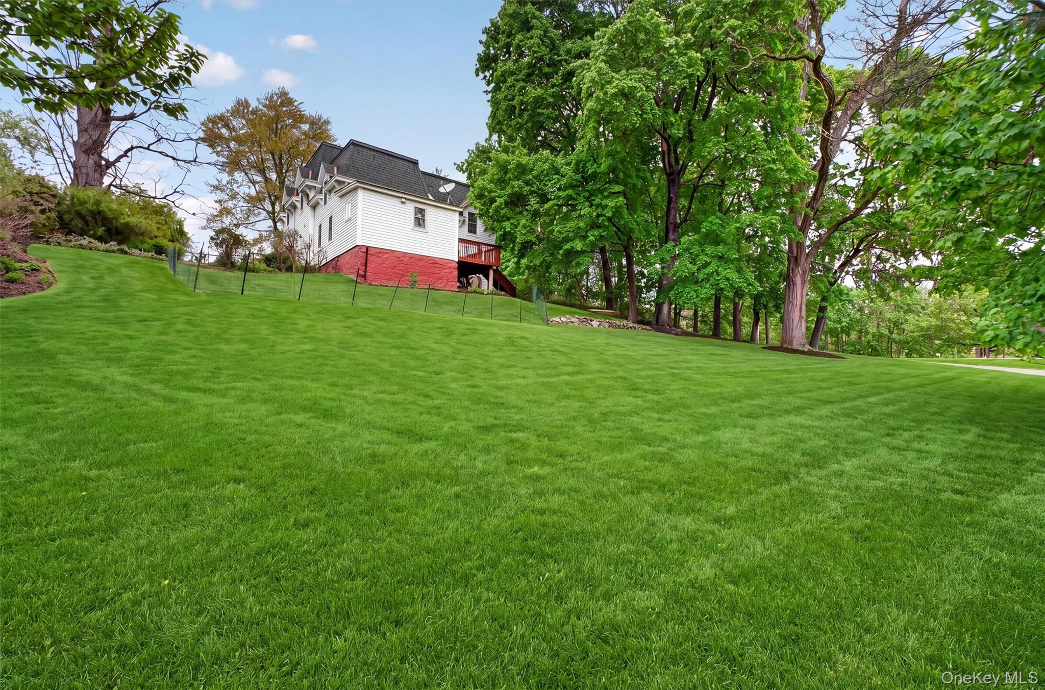 121 Old Glenham Road Fishkill, NY 12524 - Photo 47 of 50 Expansive green lawn with beautiful mature trees and a colonial structure featuring white siding and a red foundation.