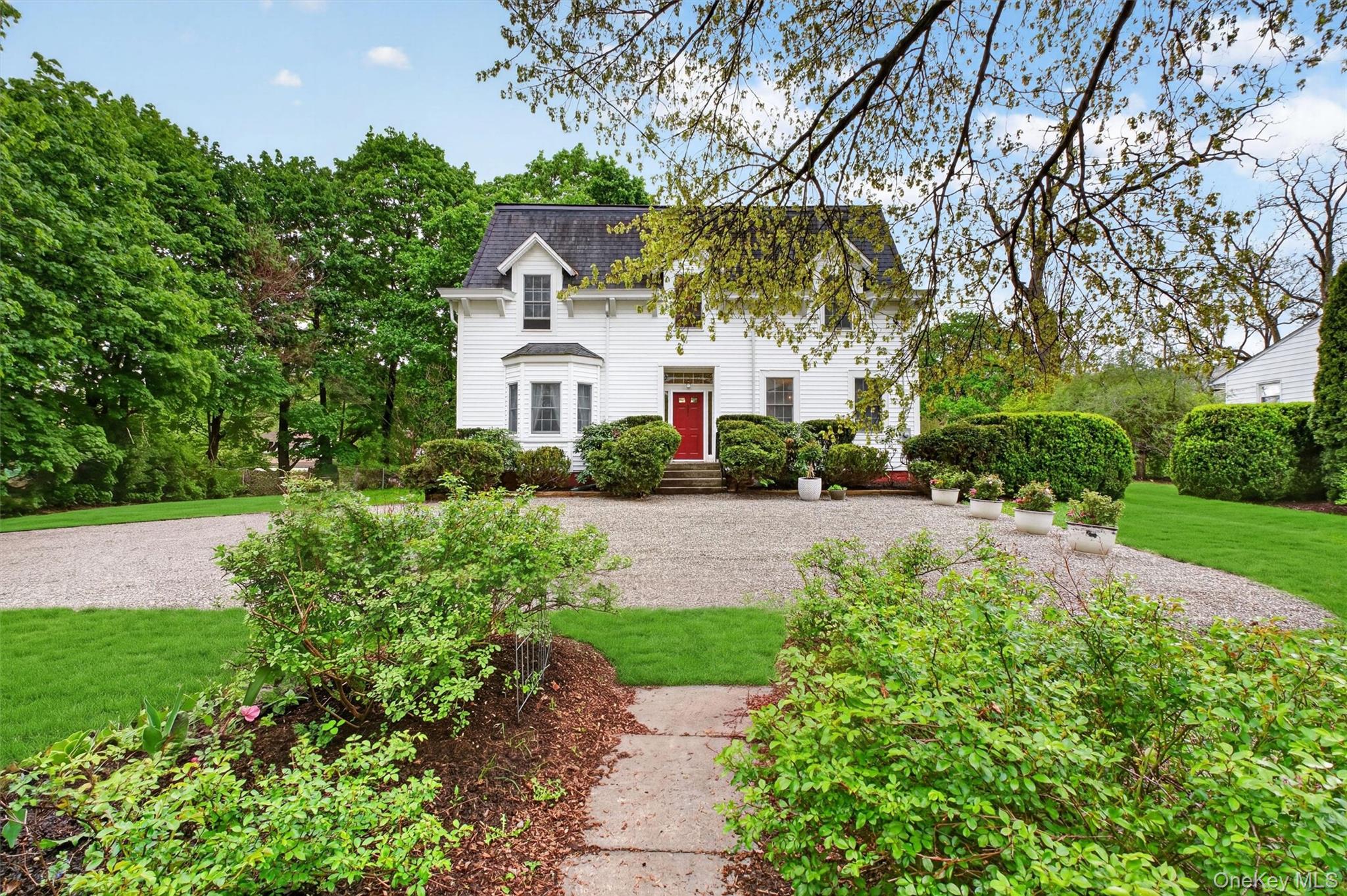 121 Old Glenham Road Fishkill, NY 12524 - Photo 48 of 50 Exterior of colonial residence with red door and mansard roof. Gravel driveway with manicured gardens surrounding.