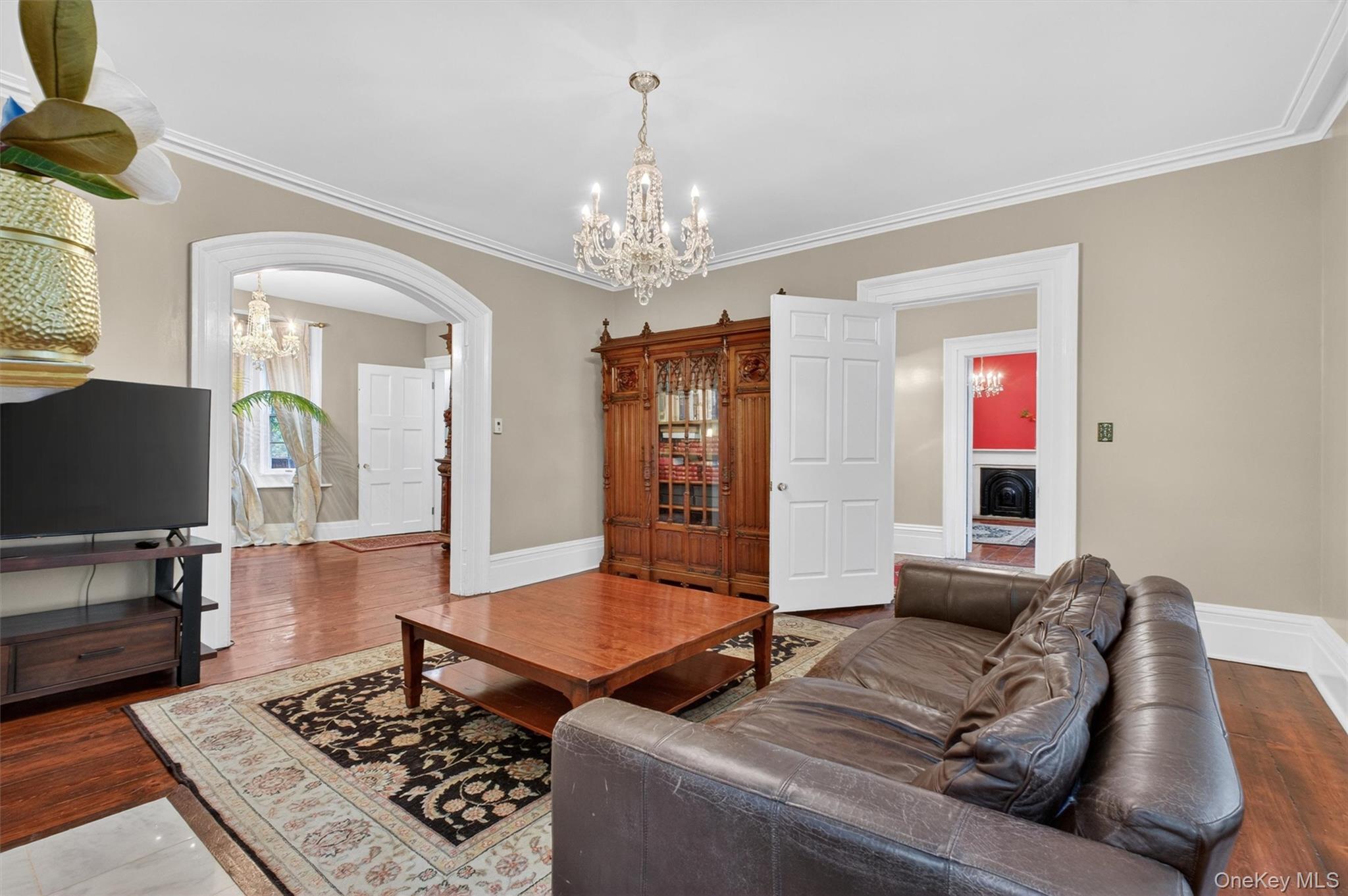 121 Old Glenham Road Fishkill, NY 12524 - Photo 8 of 50 Living area featuring crystal chandelier, hardwood floors, a decorative fireplace with a mantel, arched doorways leading to other living areas, and white trim molding