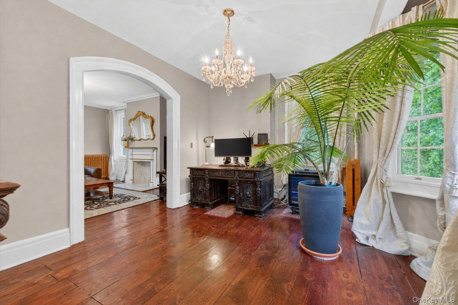 121 Old Glenham Road Fishkill, NY 12524 - Photo 9 of 50 Hardwood flooring extending through an arched doorway, featuring a crystal chandelier and large bay windows.