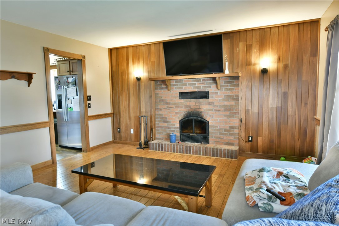 6570 Spencer Clark Road Fowler, OH 44418 - Photo 12 of 49 Living room featuring hardwood flooring, wooden wall, and a fireplace