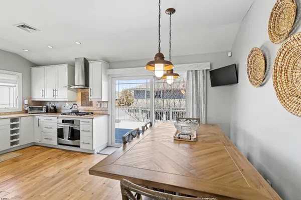 a kitchen with stainless steel appliances granite countertop a stove a sink dishwasher and white cabinets with wooden floor
