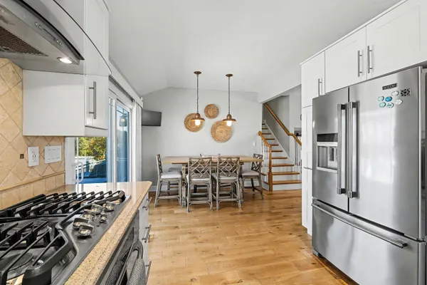 a kitchen with stainless steel appliances granite countertop a stove a refrigerator a dining table and chairs