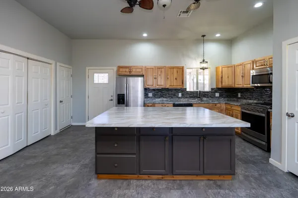 a kitchen with kitchen island granite countertop a stove a sink a refrigerator and cabinets