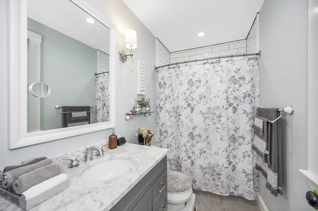 a bathroom with a granite countertop sink a toilet and shower curtain
