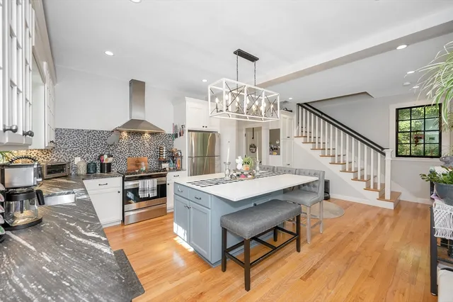 a living room with stainless steel appliances kitchen island granite countertop furniture wooden floor and chandelier