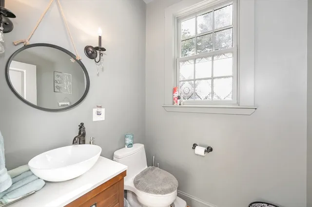 a bathroom with a toilet a sink a mirror and a window