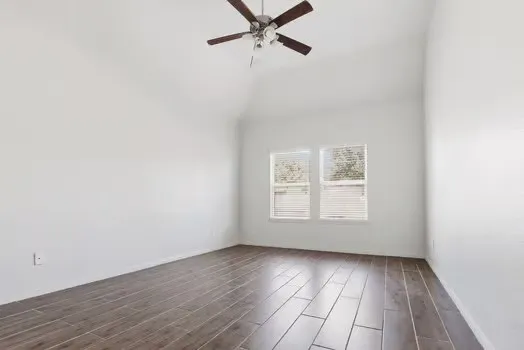 an empty room with wooden floor and windows