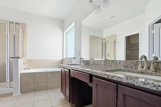 a bathroom with a granite countertop bathtub sink vanity and mirror