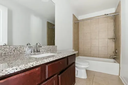 a bathroom with a granite countertop sink a toilet and shower