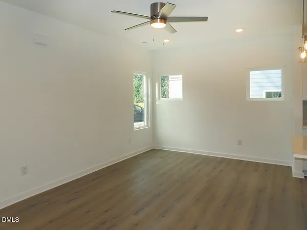an empty room with wooden floor ceiling fan and window