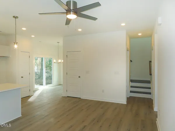a view of an empty room with wooden floor and a ceiling fan