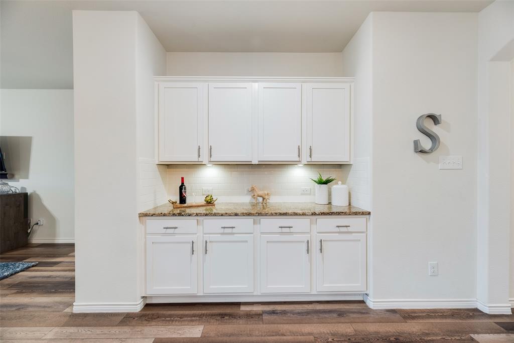 3404 Rio Grande Road Little Elm, TX 75068 - Photo 12 of 39 Convenient buffet and bar serving area with granite countertops, built-in cabinetry, and under-cabinet lighting—perfect for entertaining or additional kitchen storage.