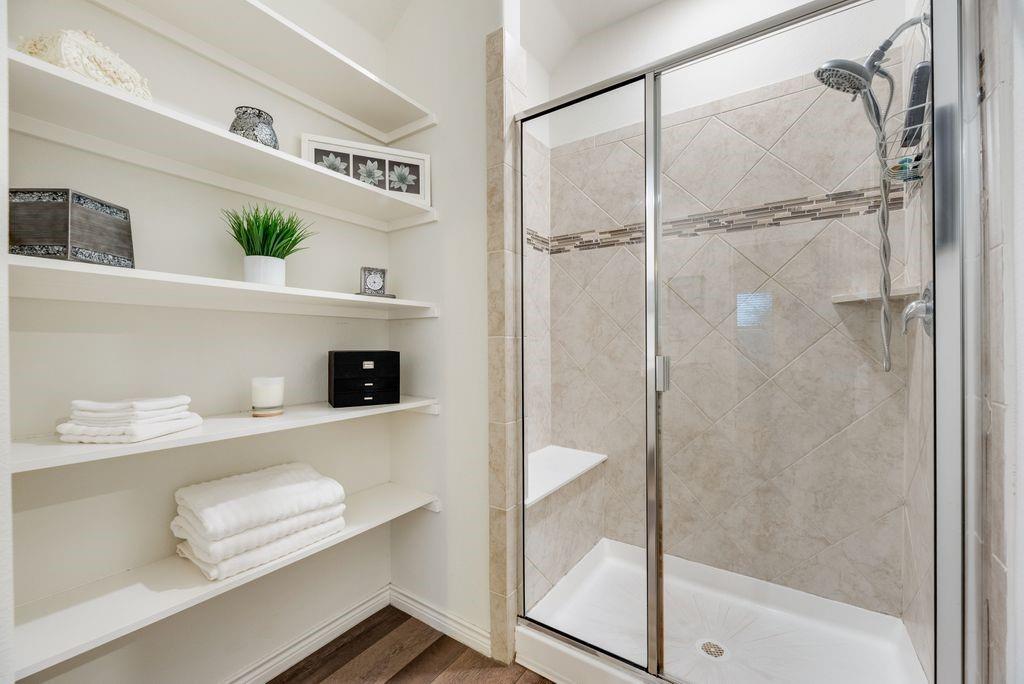 3404 Rio Grande Road Little Elm, TX 75068 - Photo 24 of 39 Primary bathroom featuring a spacious walk-in shower with built-in bench and generous linen shelving for convenient storage.