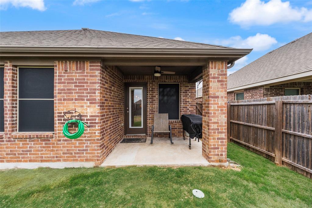 3404 Rio Grande Road Little Elm, TX 75068 - Photo 31 of 39 Covered back patio with ceiling fan and retractable privacy screen, overlooking a spacious fenced backyard perfect for relaxing or entertaining.