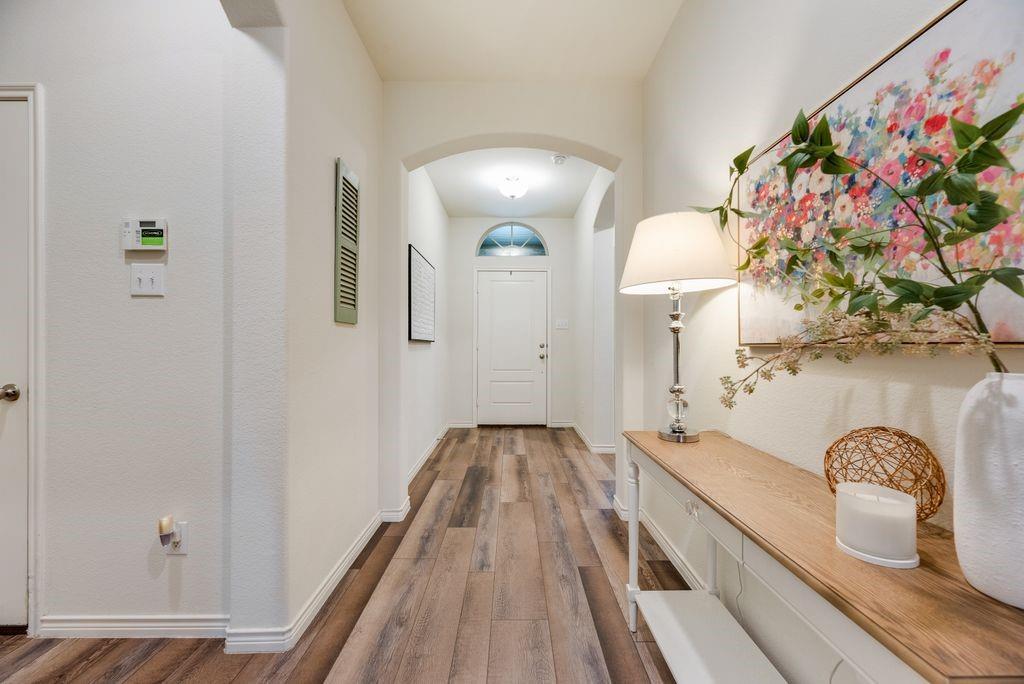 3404 Rio Grande Road Little Elm, TX 75068 - Photo 5 of 39 Welcoming entryway featuring beautiful LVP flooring, high ceilings, and an elegant arched hallway that creates a bright and inviting first impression as you enter the home.