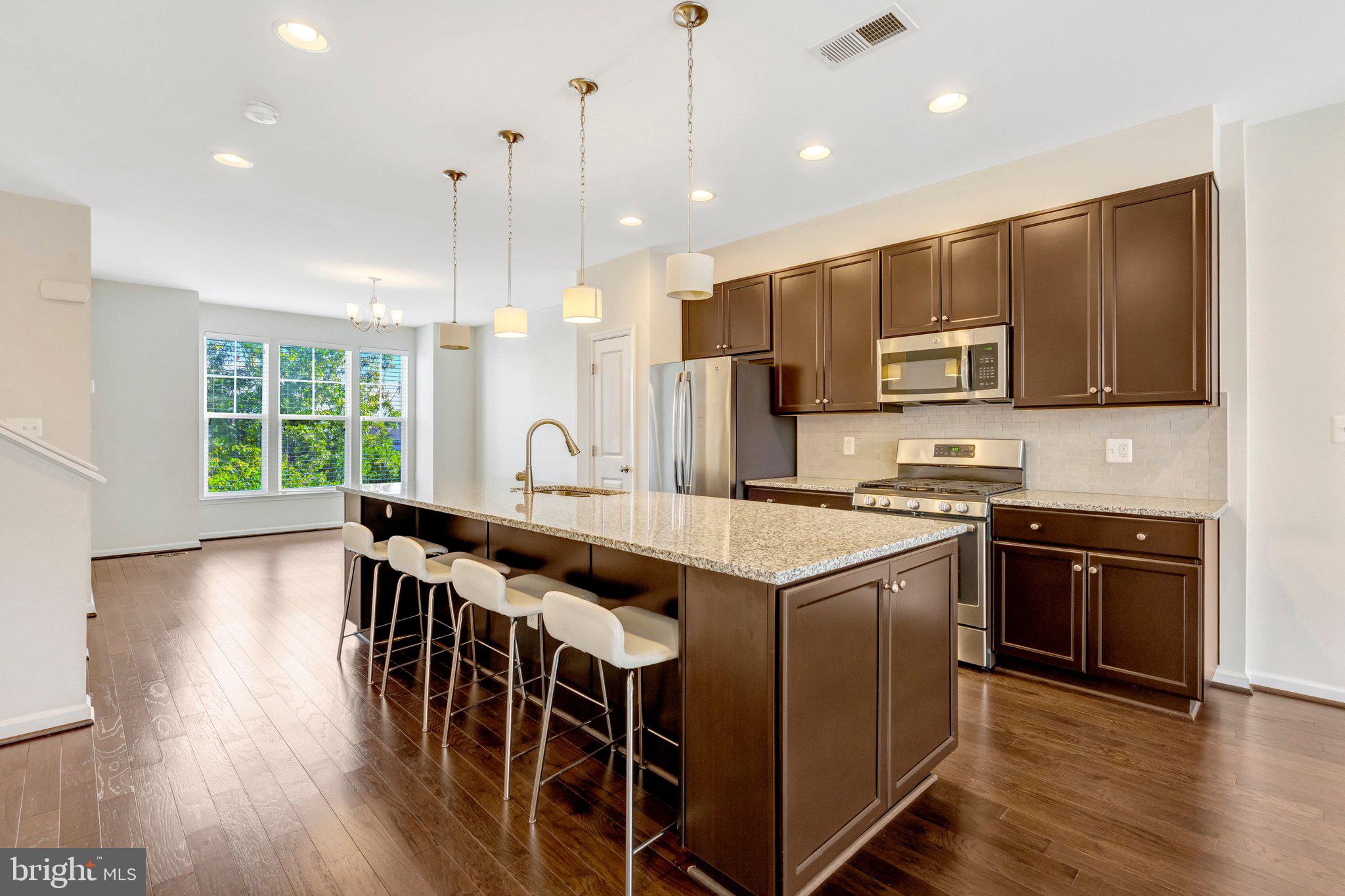 8932 Dahlgren Ridge Road Manassas, VA 20111 - Photo 10 of 41 a kitchen with stainless steel appliances granite countertop a stove top oven a sink dishwasher a dining table and chairs with wooden floor