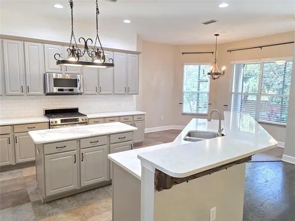 a large kitchen with stainless steel appliances kitchen island granite countertop a sink a refrigerator and a stove