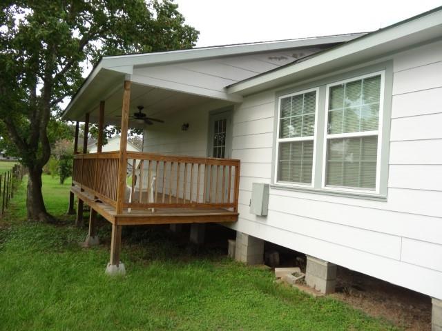 a view of a small house with a wooden deck and a yard