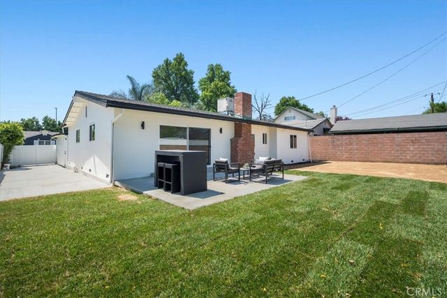 a view of a white house with a yard and potted plants