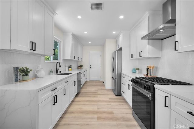 a large kitchen with stainless steel appliances lots of counter space a sink and a refrigerator