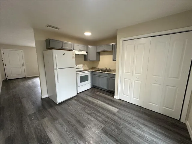 a kitchen with a refrigerator a stove top oven and wooden floor