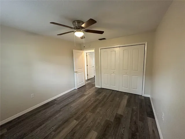 an empty room with wooden floor closet and fan