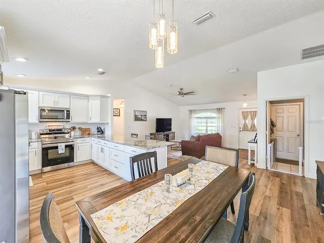 a large white kitchen with cabinets a stove a sink a dining table and chairs