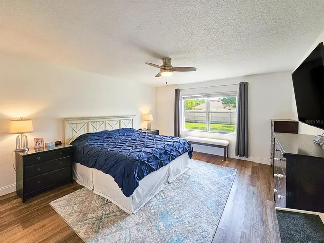 a spacious bedroom with a bed and a flat screen television