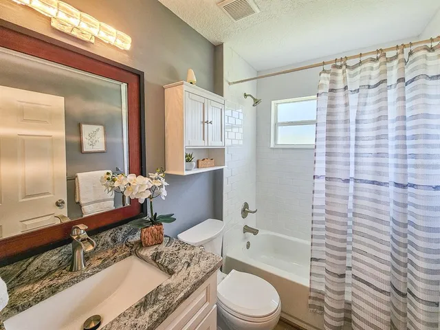 a bathroom with a granite countertop sink mirror vanity shower and toilet