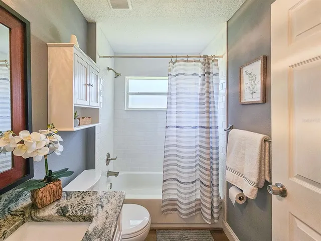 a bathroom with a granite countertop sink a toilet and shower