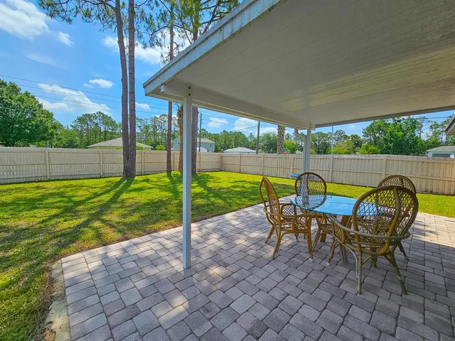 a view of backyard with table and chairs and a large tree