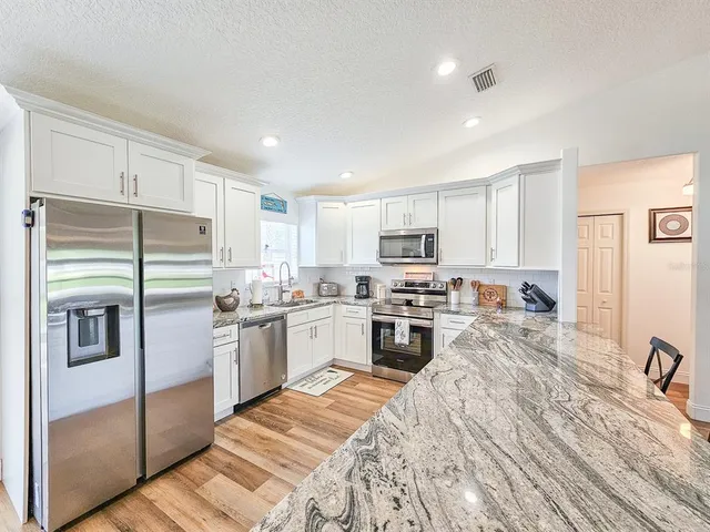 a kitchen with stainless steel appliances granite countertop a refrigerator sink and stove