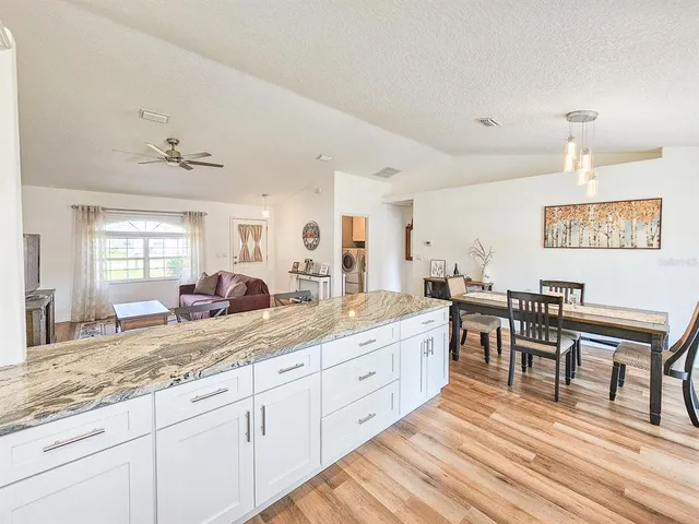 a large white kitchen with stainless steel appliances granite countertop a sink dishwasher a dining table and chairs with wooden floor