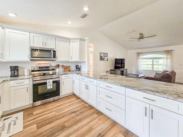 a kitchen with granite countertop white cabinets and white appliances