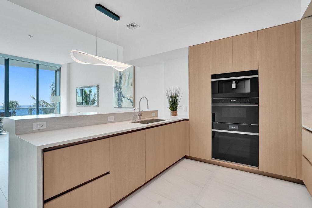 900 North Ocean Boulevard, Unit 302 Pompano Beach, FL 33062 - Photo 14 of 62 a kitchen with stainless steel appliances granite countertop a refrigerator and a sink