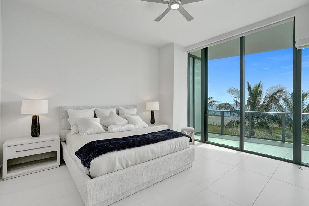 900 North Ocean Boulevard, Unit 302 Pompano Beach, FL 33062 - Photo 20 of 62 a bedroom with a large bed and a chandelier fan