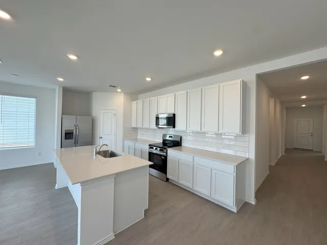 a kitchen with stainless steel appliances kitchen island sink refrigerator and cabinets