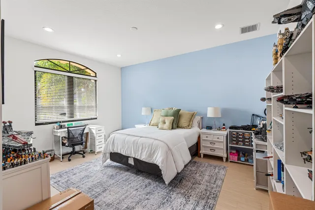 a bedroom with a bed a bookshelf and a dresser with wooden floor