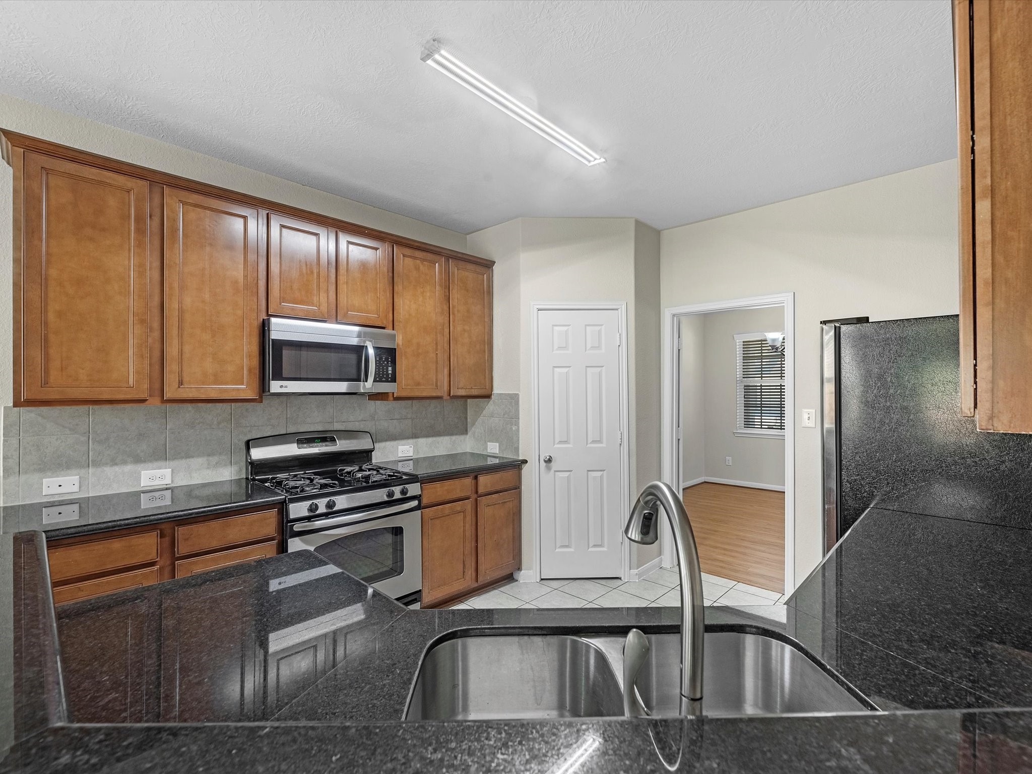 13307 Bomoseen Lake Road Houston, TX 77044 - Photo 12 of 40 a kitchen with stainless steel appliances granite countertop a stove top oven a sink dishwasher a dining table and chairs with wooden floor