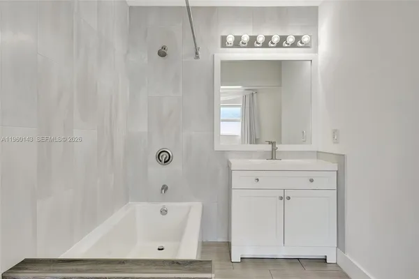 a bathroom with a tub a sink and mirror