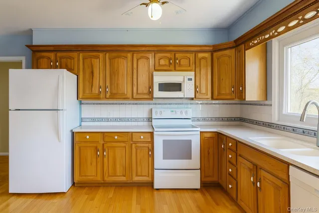 a kitchen with stainless steel appliances granite countertop a stove a sink dishwasher and a refrigerator with wooden floor