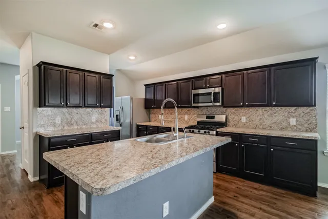 a kitchen with granite countertop a sink stainless steel appliances and wooden cabinets