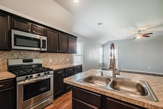 a view of an empty room with wooden floor and a ceiling fan